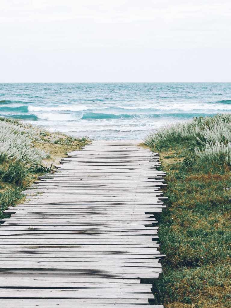 Rustic wooden pathway leading to the ocean, scenic coastal journey for outdoor enthusiasts.