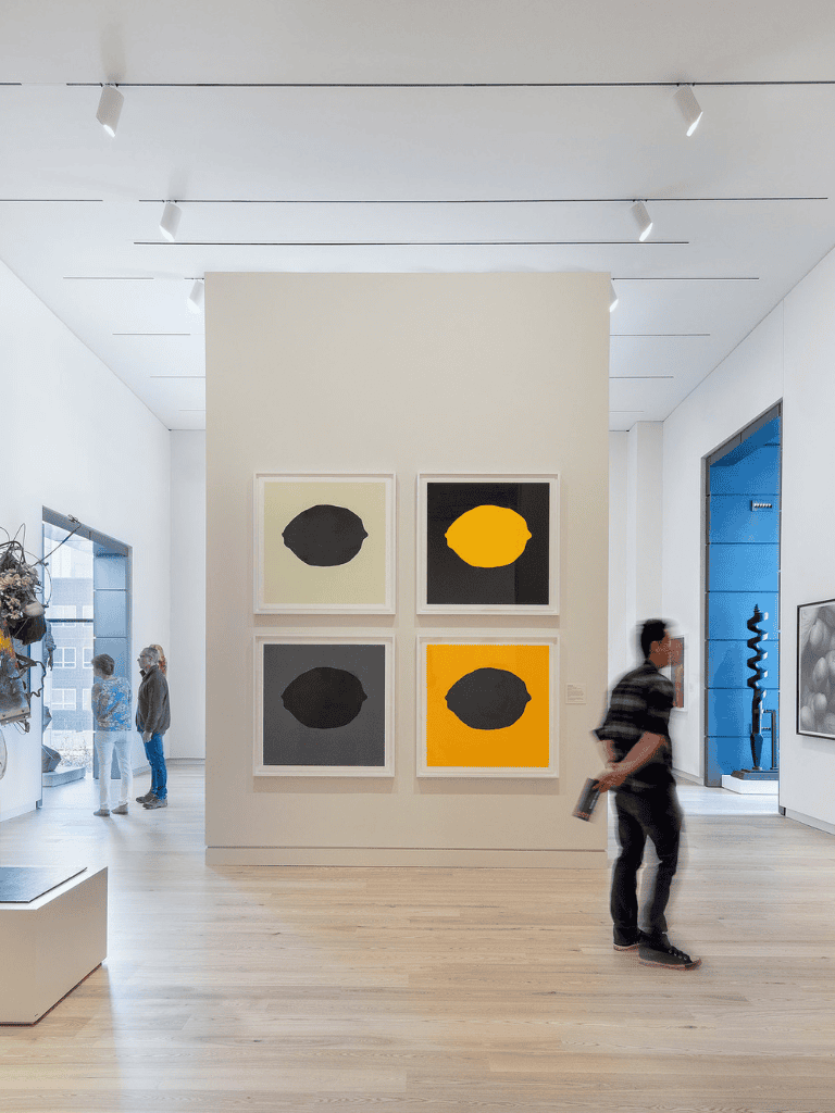 Modern art gallery with colorful abstract paintings and visitors exploring the space.