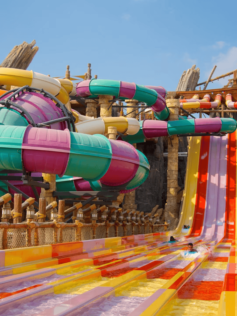 Colorful water slides at water park with kids having fun, family-friendly outdoor water attractions.