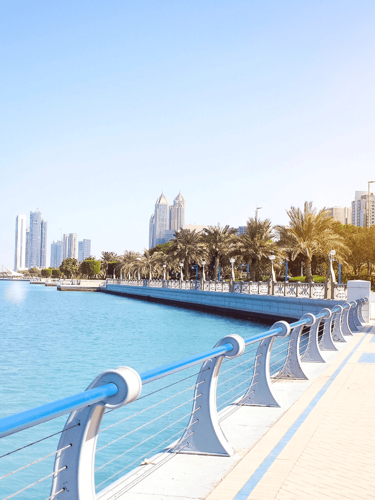 Scenic waterfront promenade in Dubai with modern skyline and palm trees.