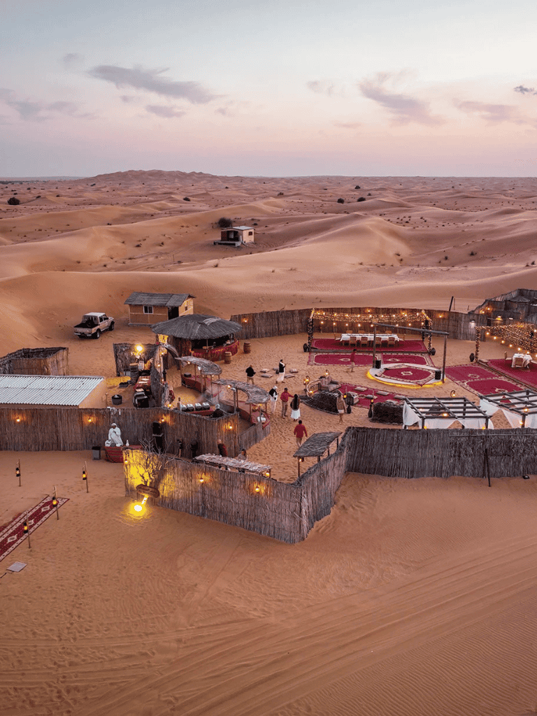 Desert oasis campground with traditional tents and outdoor seating under desert sky.
