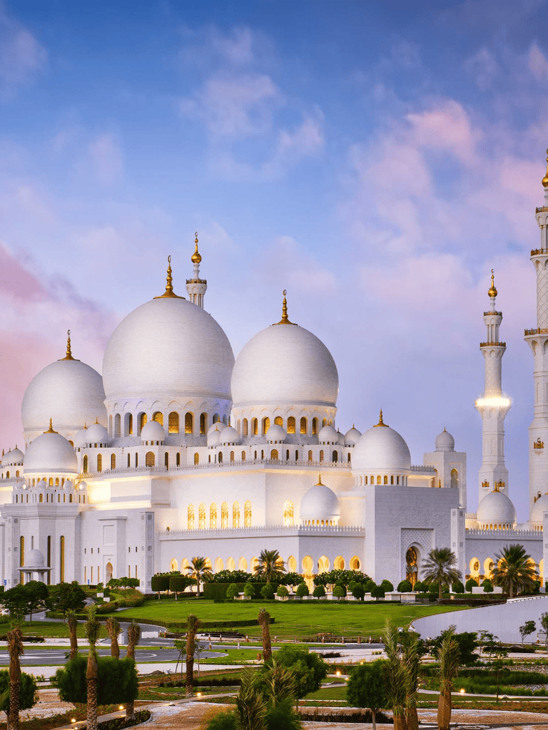 Majestic white mosque with golden accents, lush gardens, and Arabic architectural design, Dubai landmark.
