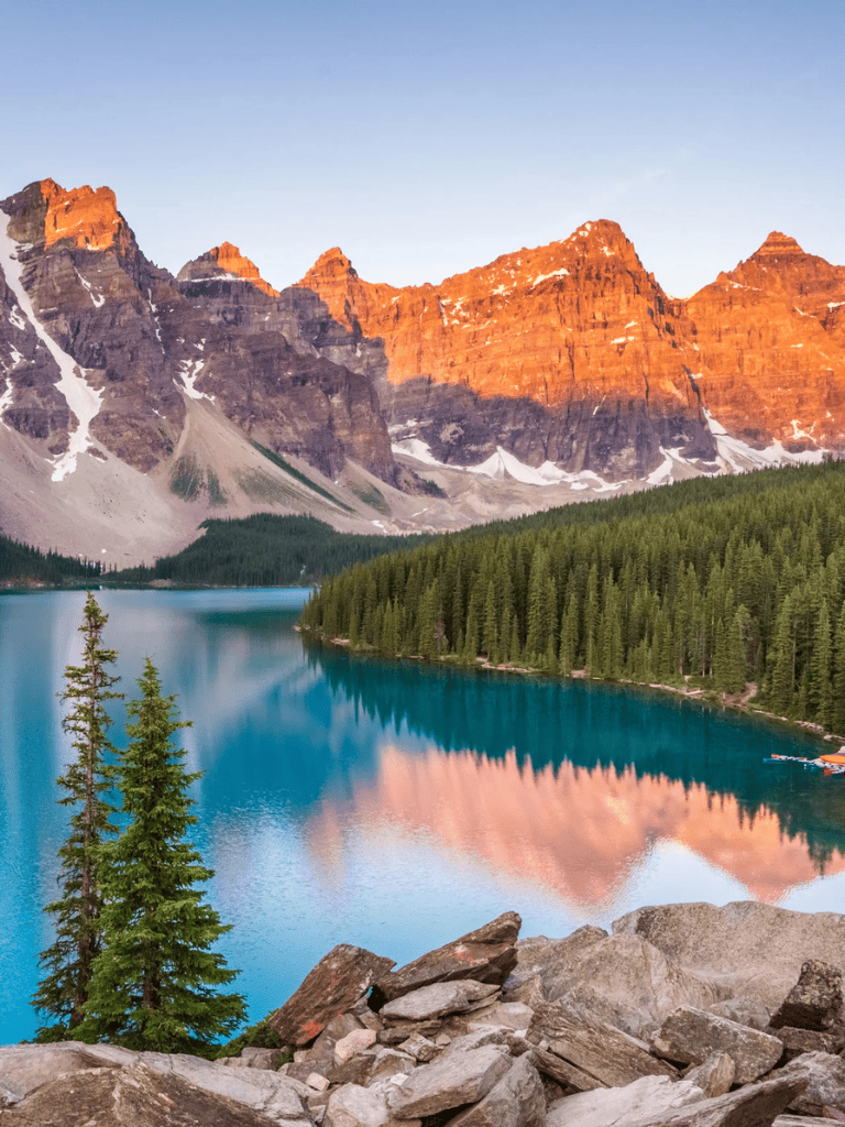 Serene mountain lake with reflection of snow-capped peaks seen at sunset in national park scenery.