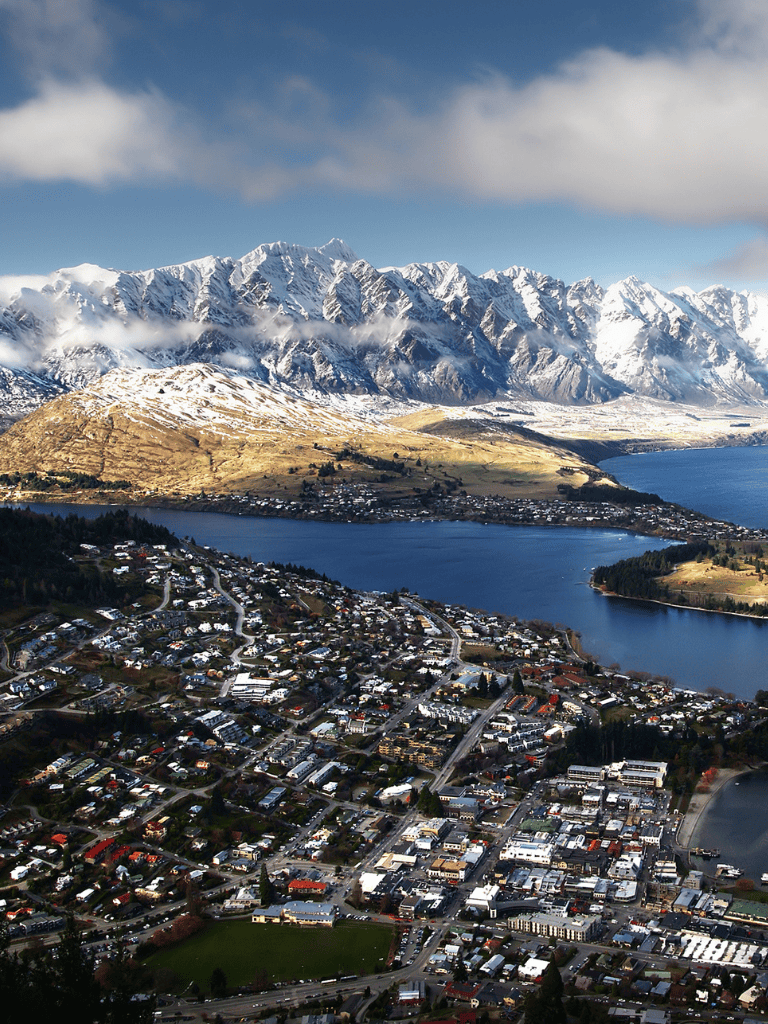 Snow-capped mountains with a scenic lakeside town, perfect for travel and adventure.