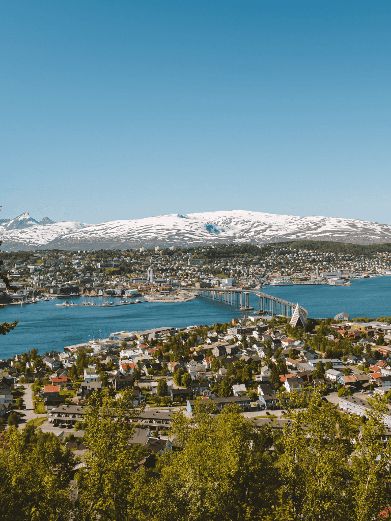 Panoramic view of Trondheim city with snow-capped mountains and blue water in Norway, showcasing scenic landscapes and urban area.