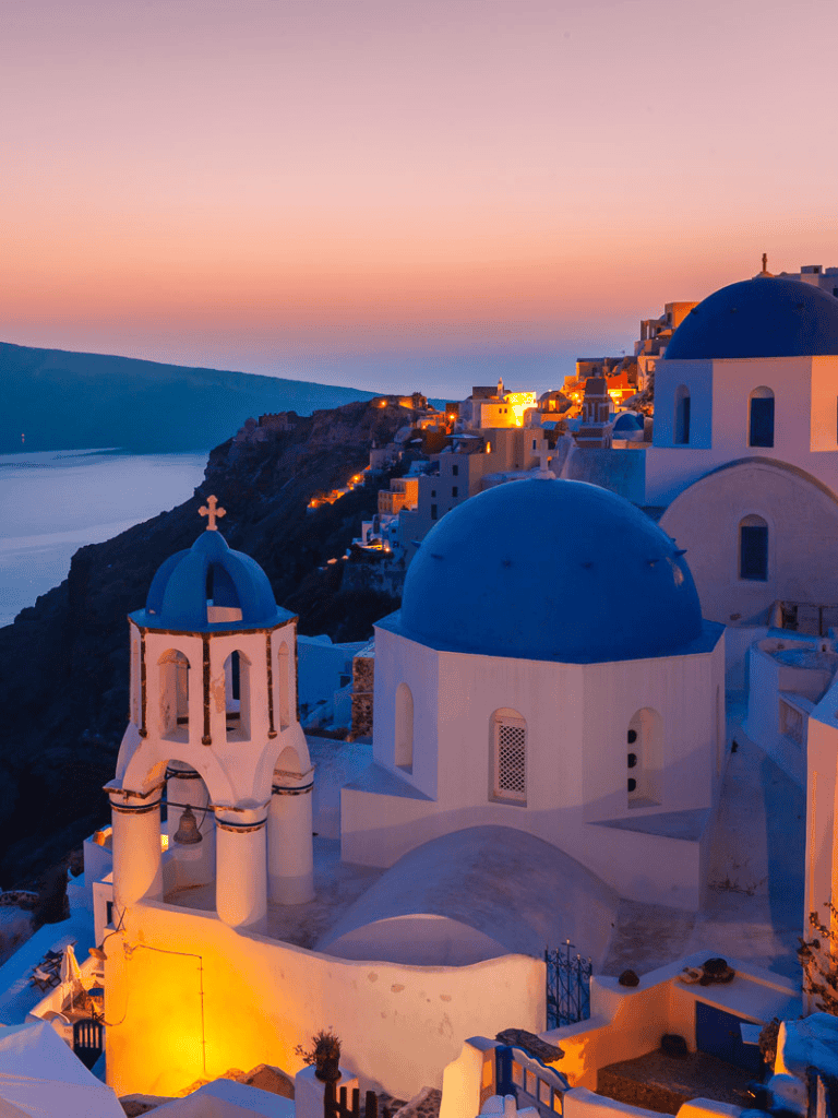 Colorful sunset over Santorini Greece with iconic blue-domed churches and white buildings, perfect for travel and vacation planning.