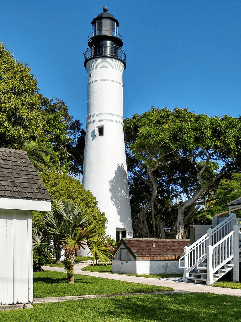Lighthouse at dusk with lush trees and garden, iconic coastal scenery, Great for travel and sightseeing.