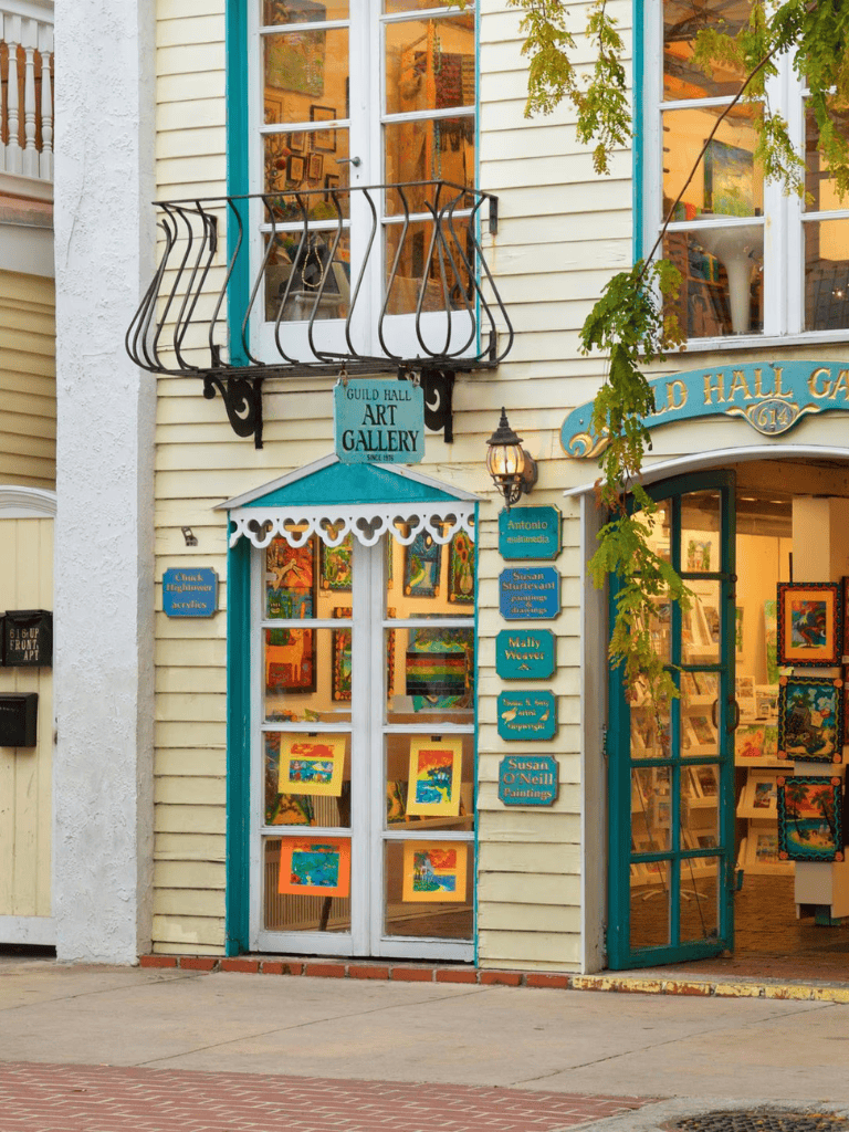 Colorful art gallery storefront showcasing vibrant paintings inside and outside.