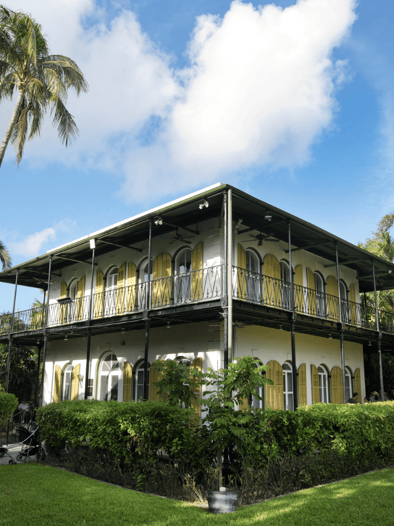 Elegant historic house with lush landscaping and a vibrant blue sky.