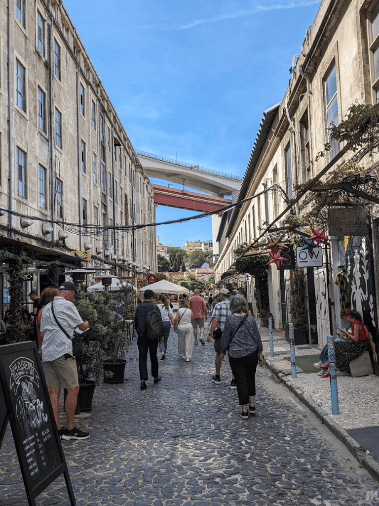 Pedestrian street in old town with shops and cafes, urban alleyway, popular tourist area with cobblestone pathway.