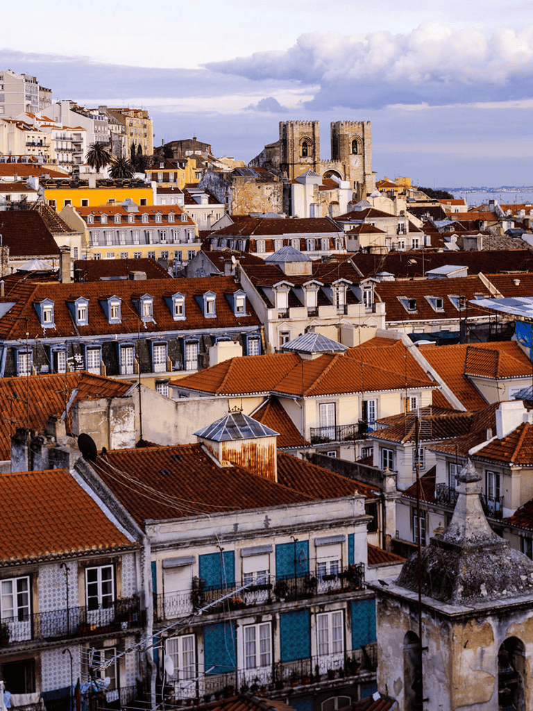 Colorful Lisbon rooftops with historic architecture and the São Jorge Castle in the background.