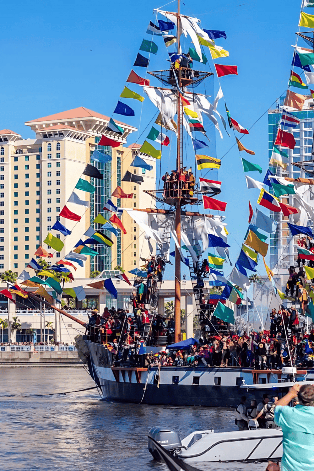 Colorful sailing ship with flags in urban harbor, perfect for travel and maritime adventures.