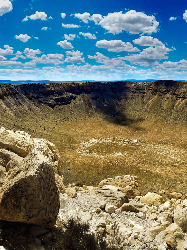 Vast volcanic crater with rugged rocky edges under blue sky with clouds, scenic destination from QuestForDirections.