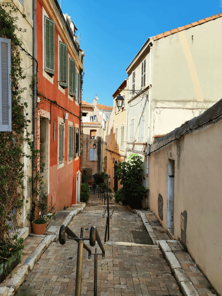 Colorful European alleyway with cobblestone path and charming residential buildings.