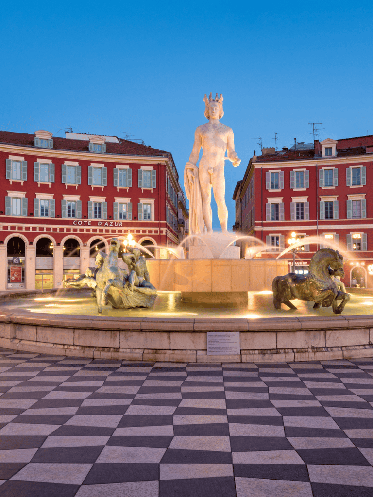 Majestic fountain in Nice, France featuring a marble sculpture of a classical figure with surrounding lion and horse statues.