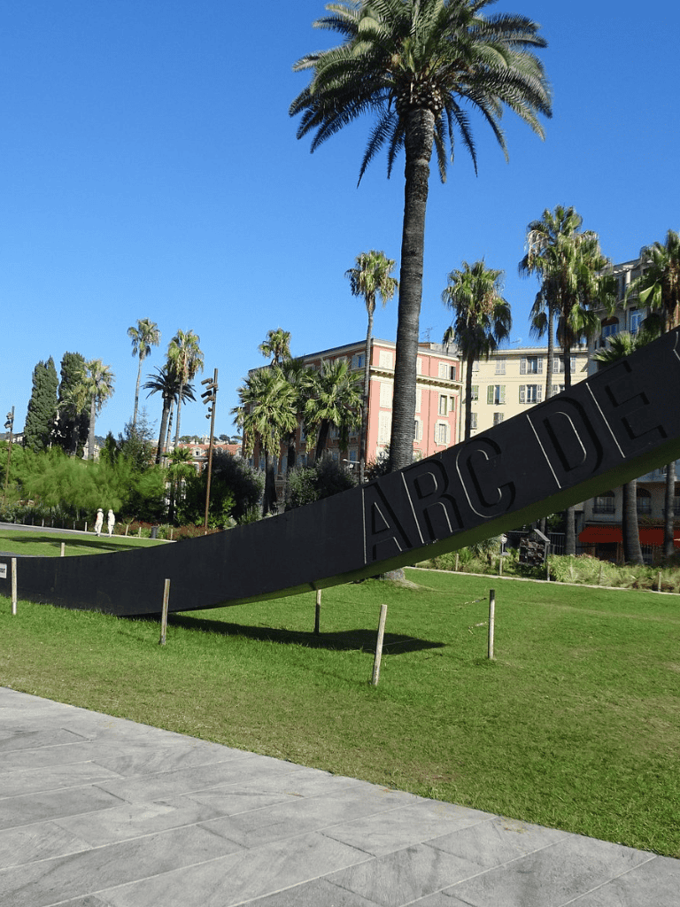 Palm trees at Arc De Triomphe sculpture in sunny outdoor park in California.