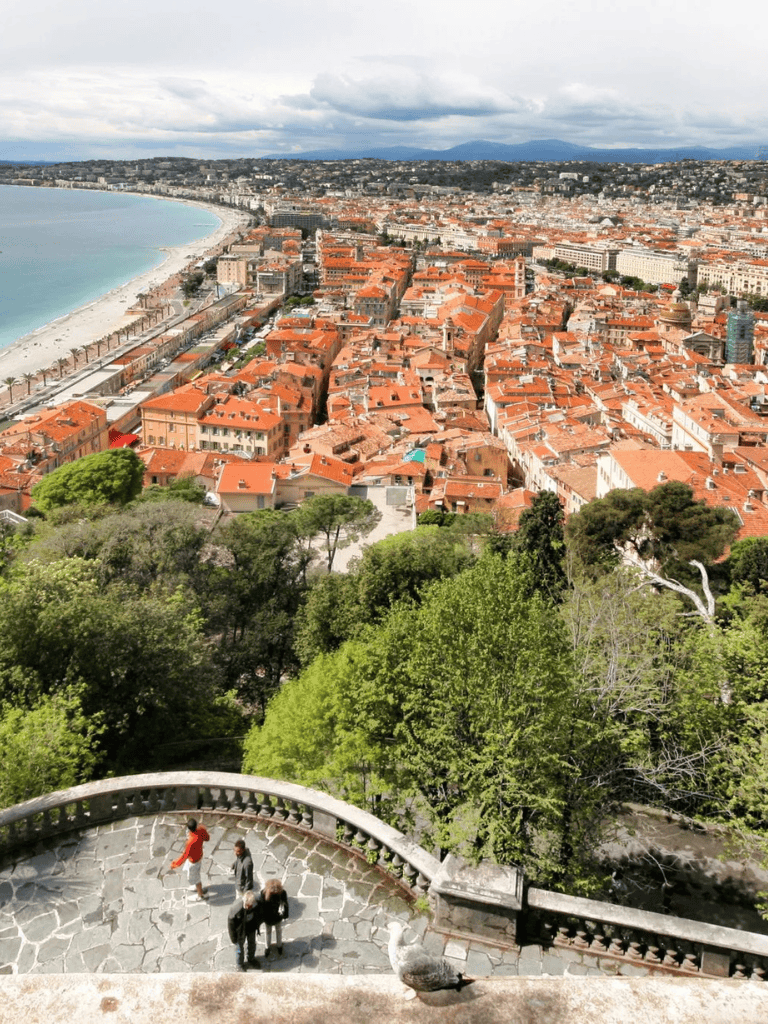 Panoramic view of Nice, France, with Mediterranean coastline, historic old town, and lush greenery.