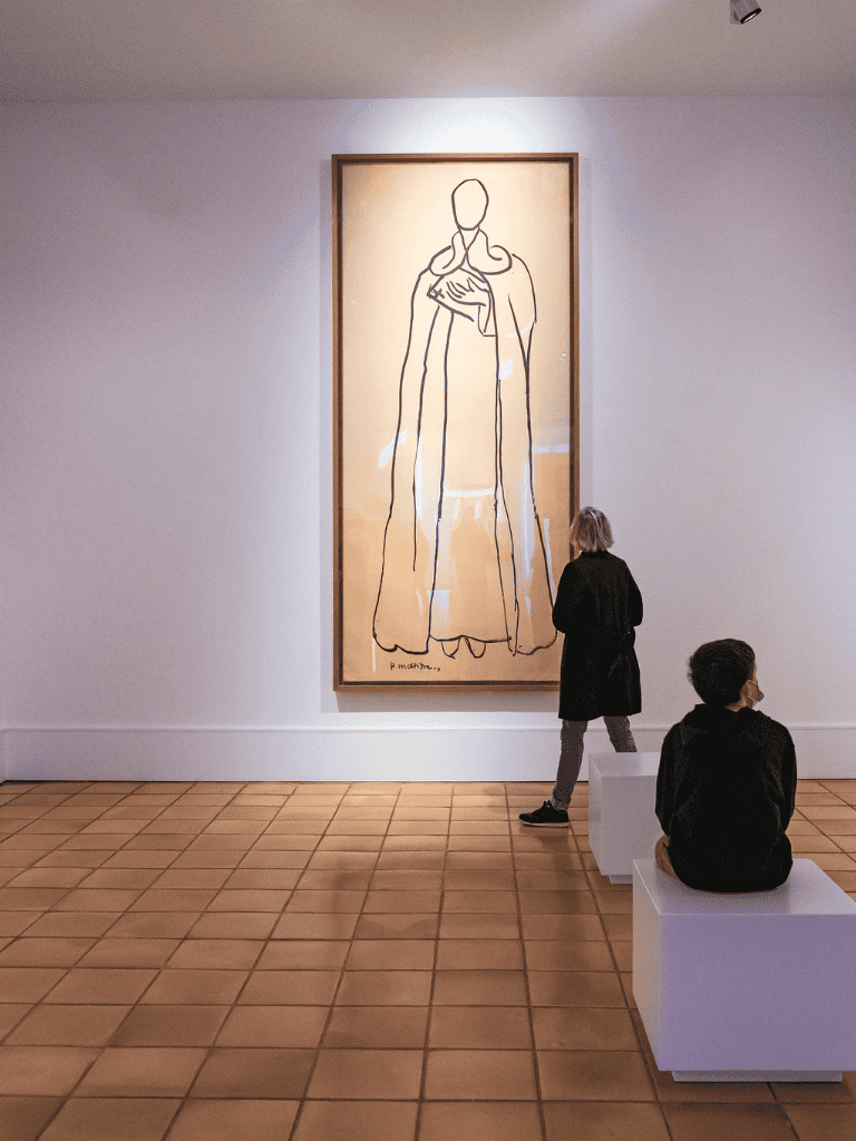 Elegant art gallery with minimalist line drawing of a religious figure on display.