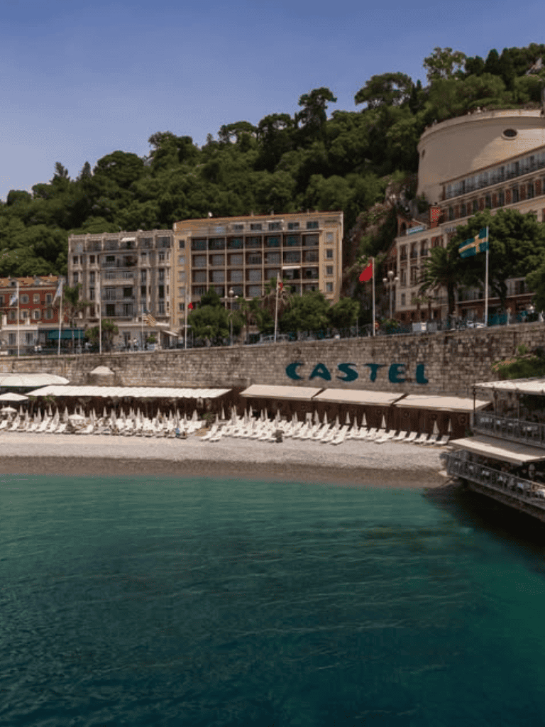 Elegant beachfront hotel along the Mediterranean with terraces, outdoor pools, and scenic mountain views.