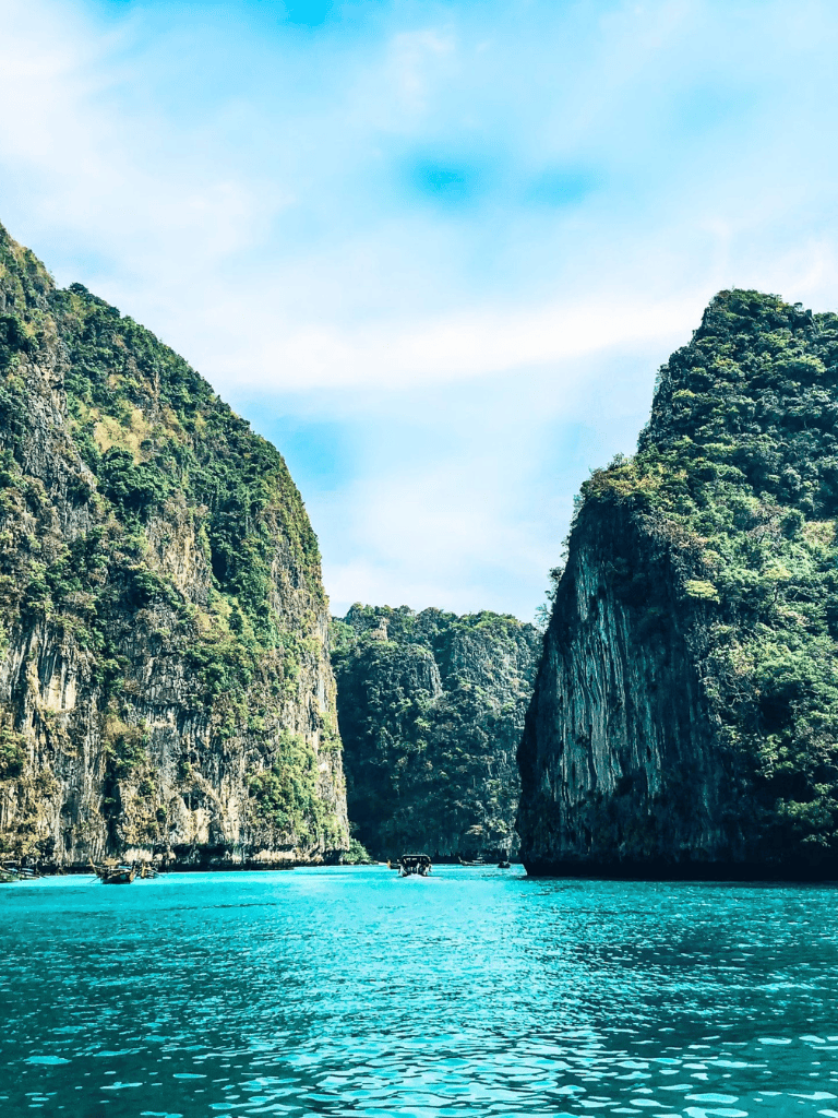 Serene turquoise water between lush green limestone cliffs in a tropical river landscape.
