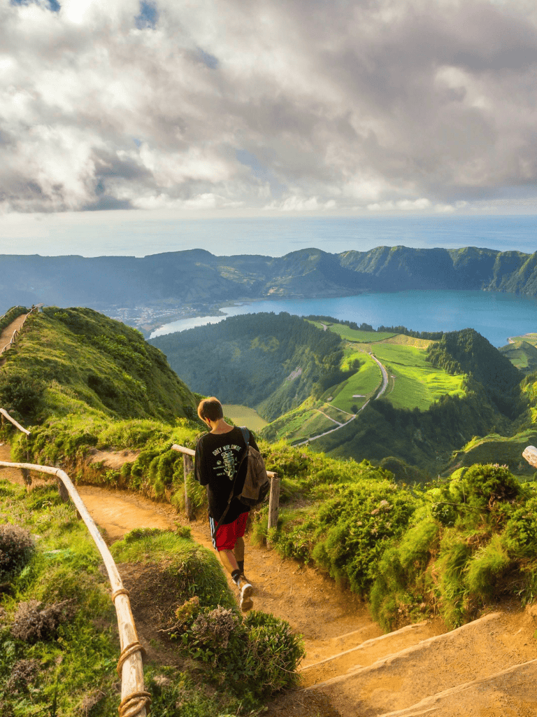 Breathtaking mountain trail view with lush greenery and a lake in the background, perfect for adventure seekers.