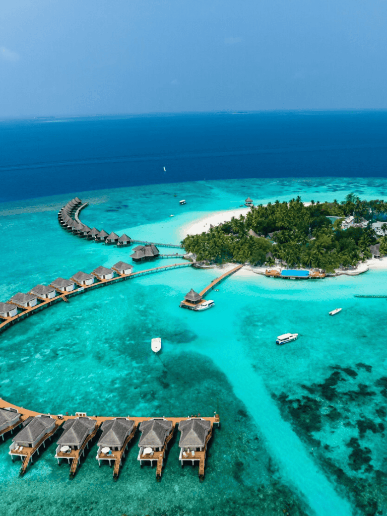 Overwater bungalows on turquoise ocean near tropical island paradise, luxury resort in the Maldives.