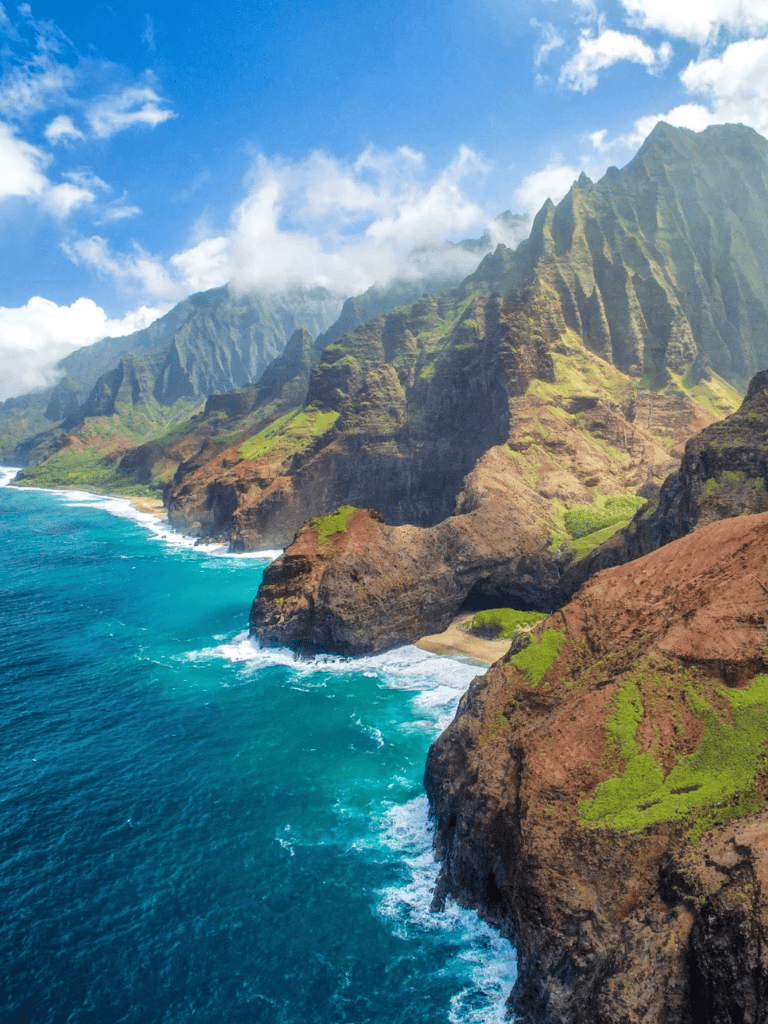Cliffs and coastline of Hawaii's Na Pali Coast, lush green mountains and turquoise waters.