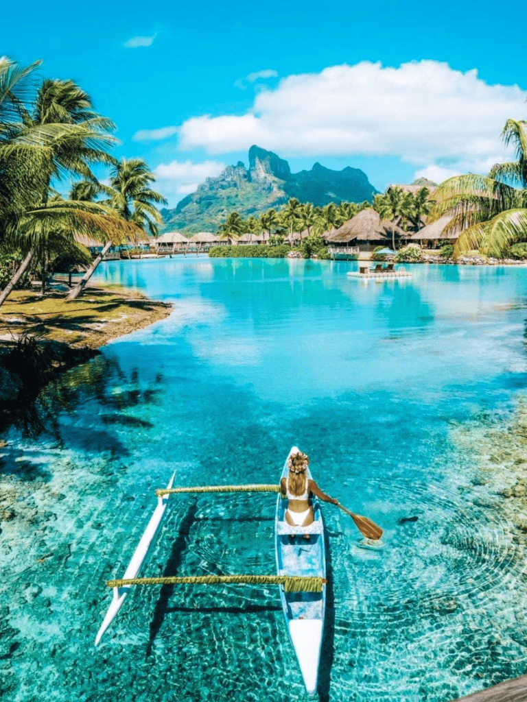 Tranquil tropical island with clear waters, palm trees, and mountain views for vacation travel.
