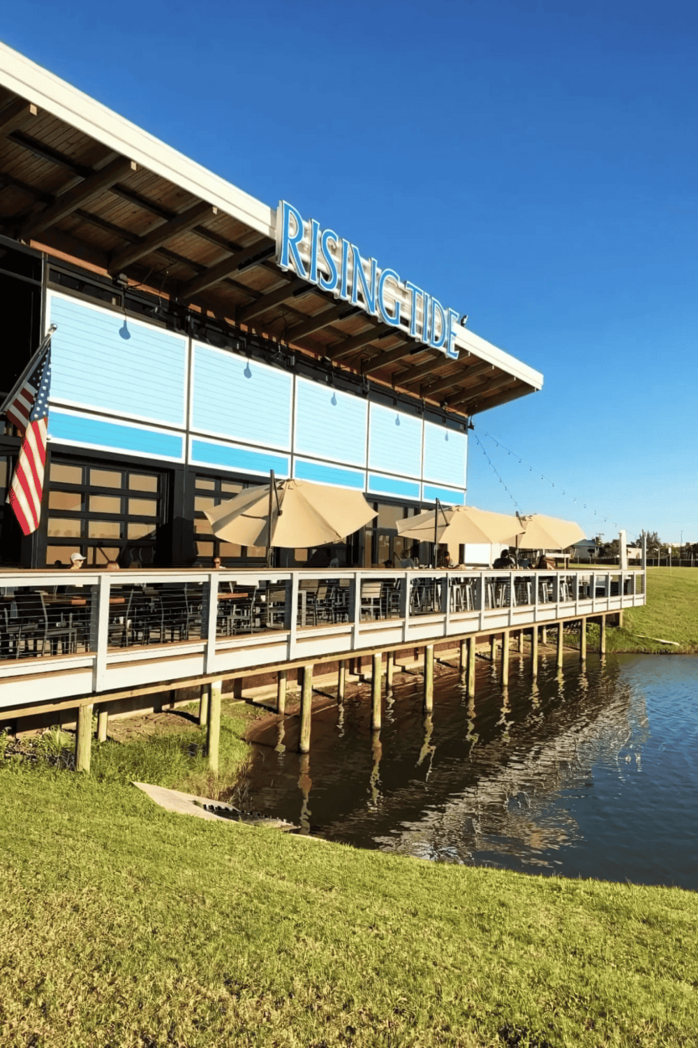 Vibrant waterfront restaurant with outdoor seating and clear blue sky, perfect for dining at Rising Tide.