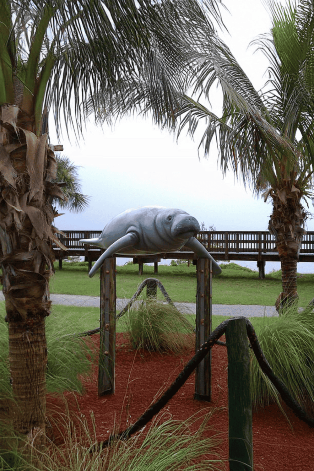 Whale sculpture at outdoor park with palm trees and viewing deck, perfect for family outings, nature walks, and marine life education.