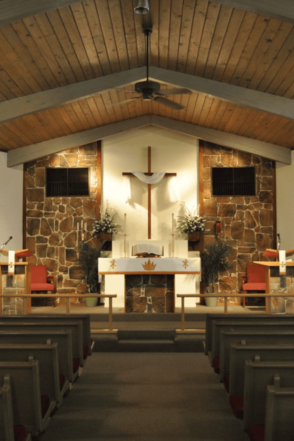 Serene church altar with cross, wood-paneled ceiling, and floral arrangements for spiritual guidance.