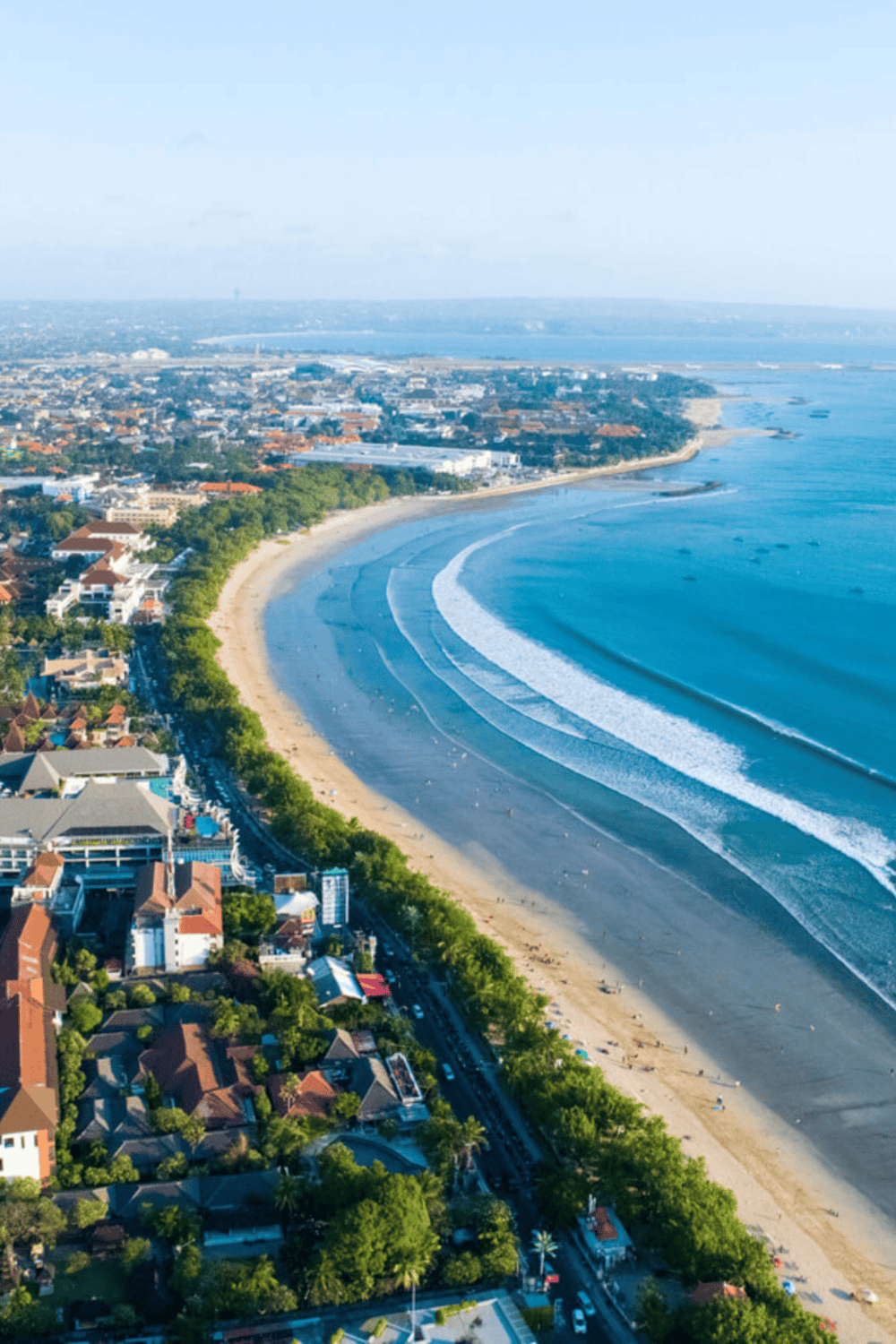 Aerial view of a coastal city with a beautiful beach, lush greenery, and urban landscape. Perfect destination for travel and adventure.