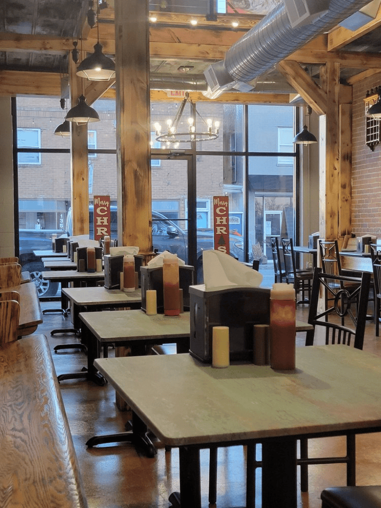 Cozy modern restaurant interior with wooden accents, candles, and large windows for an inviting dining experience.