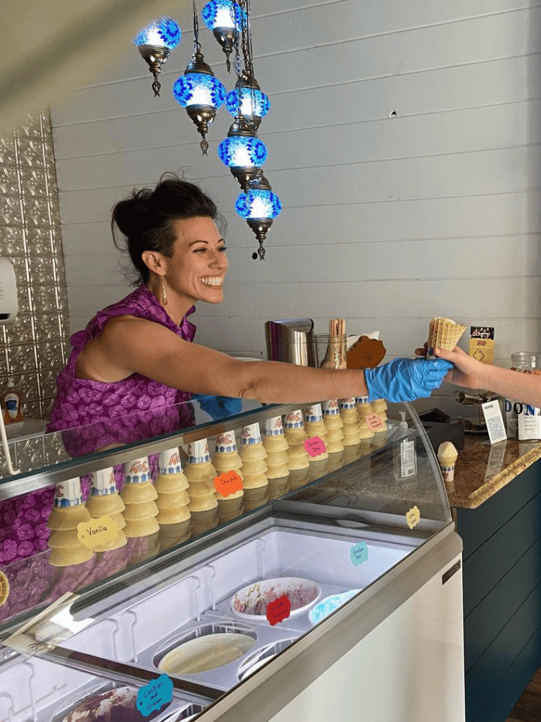 Warm smile woman serving ice cream at dessert shop, friendly customer service, ice cream parlor, sweet treats, happy moment.