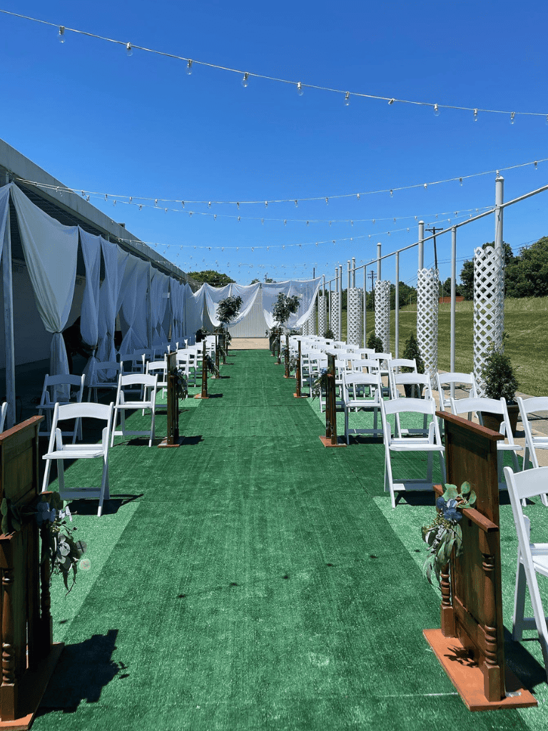 Elegant outdoor wedding ceremony setup with white chairs and decorative elements under string lights.