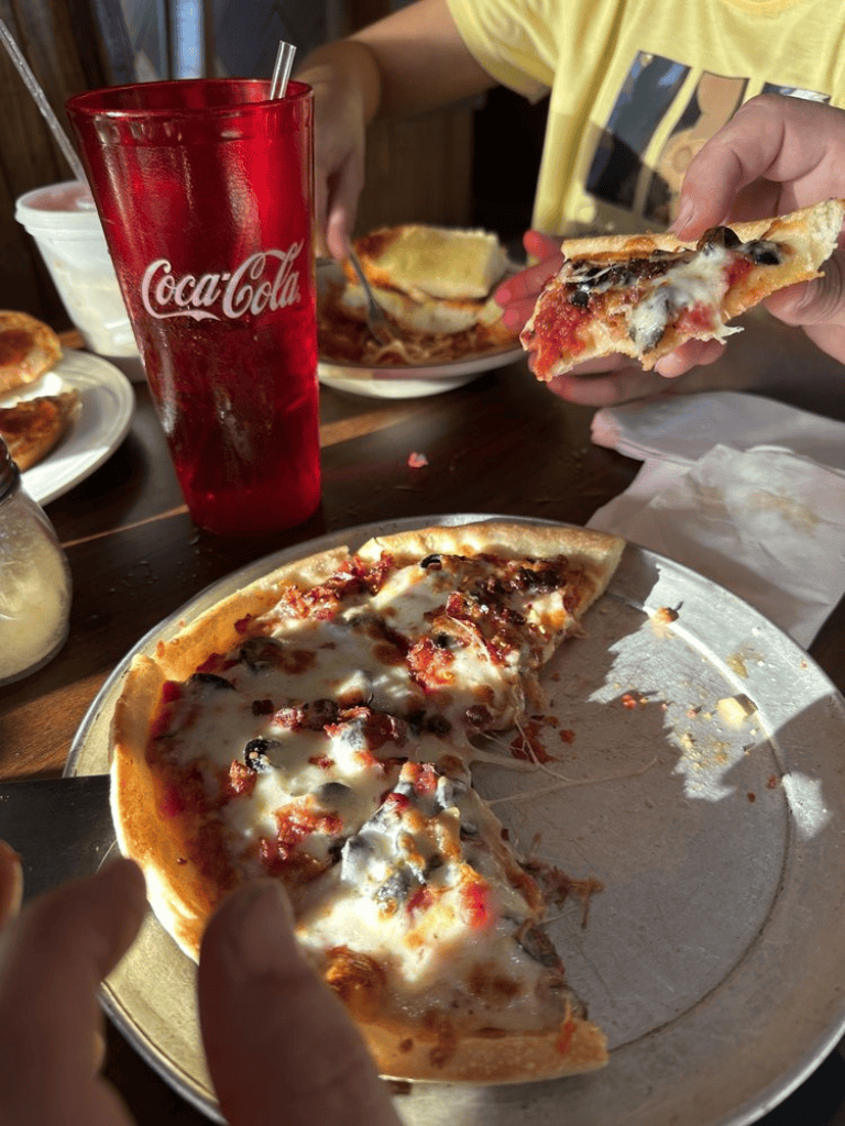 Cheese and pepperoni pizza with a Coca-Cola drink on a wooden table.