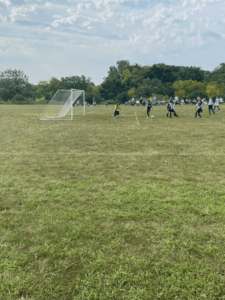 Children playing youth soccer on an outdoor field during daytime.