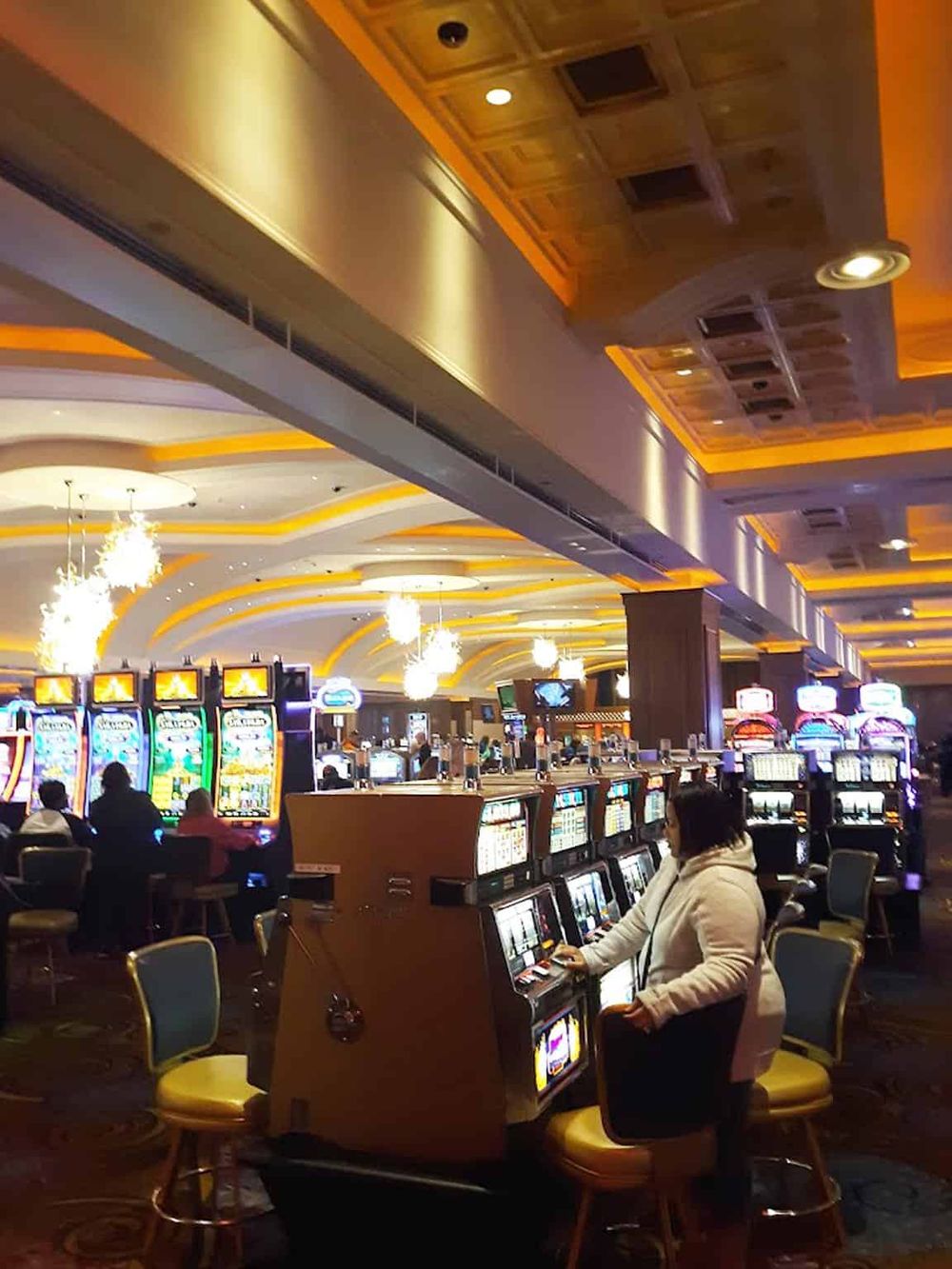 Bright casino gaming area with slot machines and players at QuestForDirections casino.