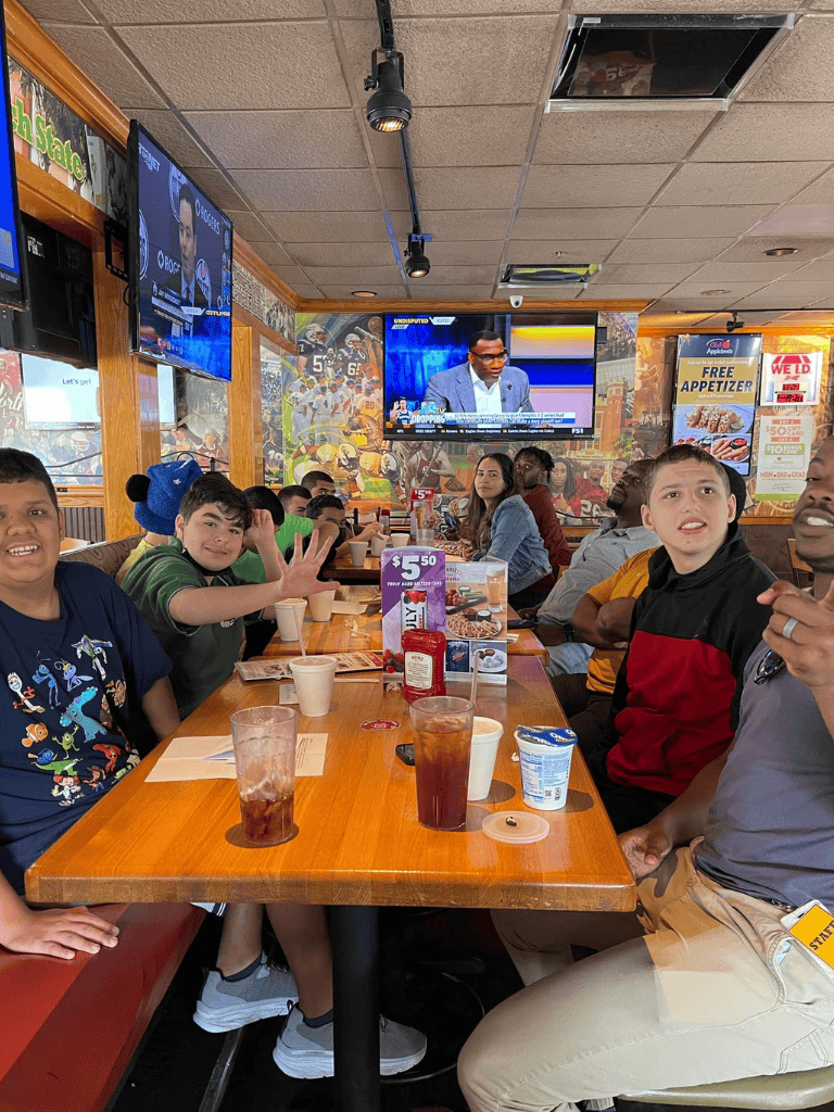 Enjoying kids and family group at a sports bar with televised football game and casual dining atmosphere.