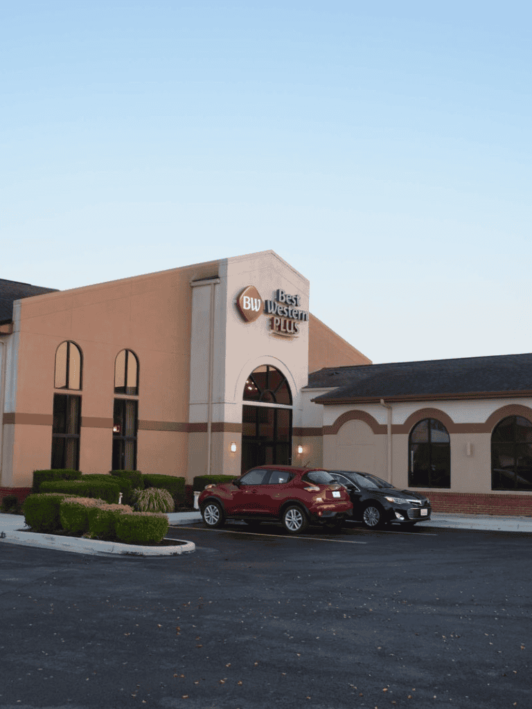 BMW Best Western Plus hotel exterior with parking lot and cars.