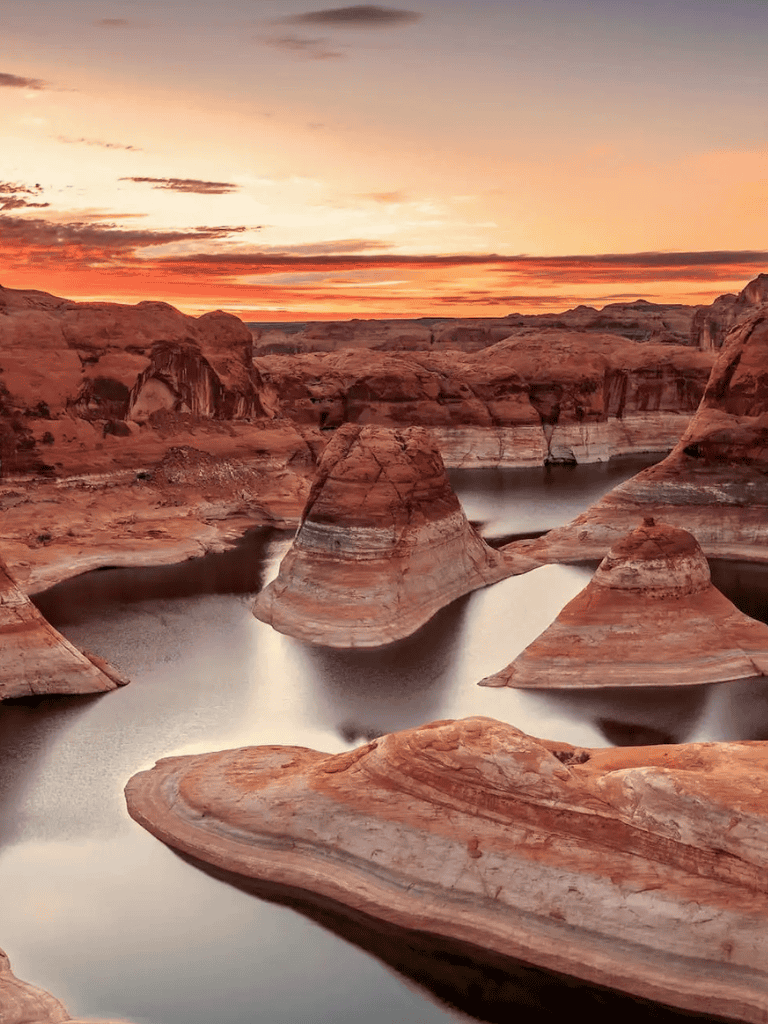 Vast desert canyon landscape with rock formations and water at sunset, perfect for adventure travel.