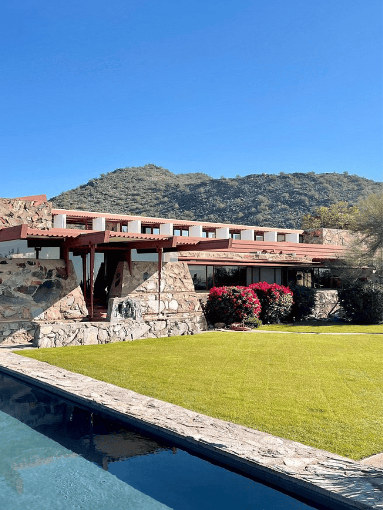 Modern desert-style resort with lush lawn and mountain backdrop.