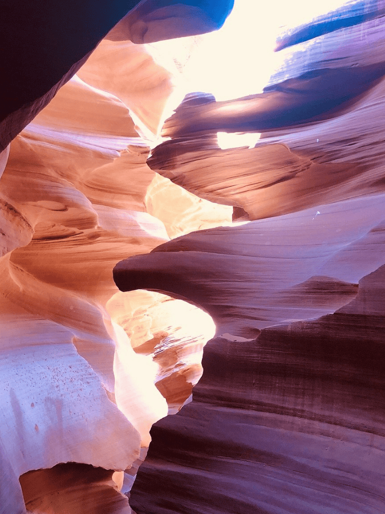Striking slot canyon formation with colorful, layered rock walls and sunlight filtering through narrow openings.