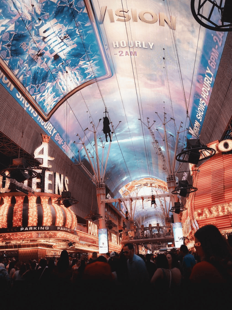 Bright neon signs and lively crowd at Las Vegas casino entertainment district.