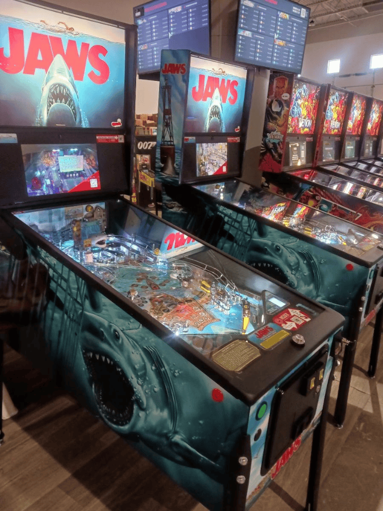 Jaws-themed pinball machine in arcade with multiple game screens and colorful pinball arcade setup.