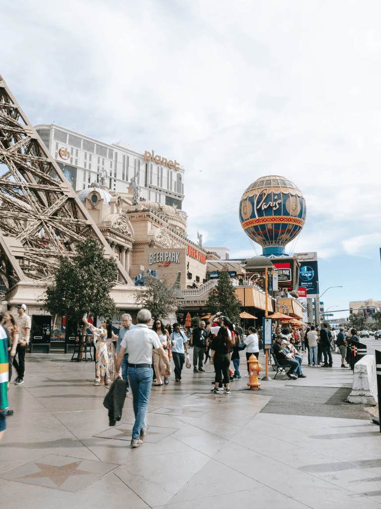 Vibrant Las Vegas street scene with iconic Paris Hotel balloon and bustling crowd.