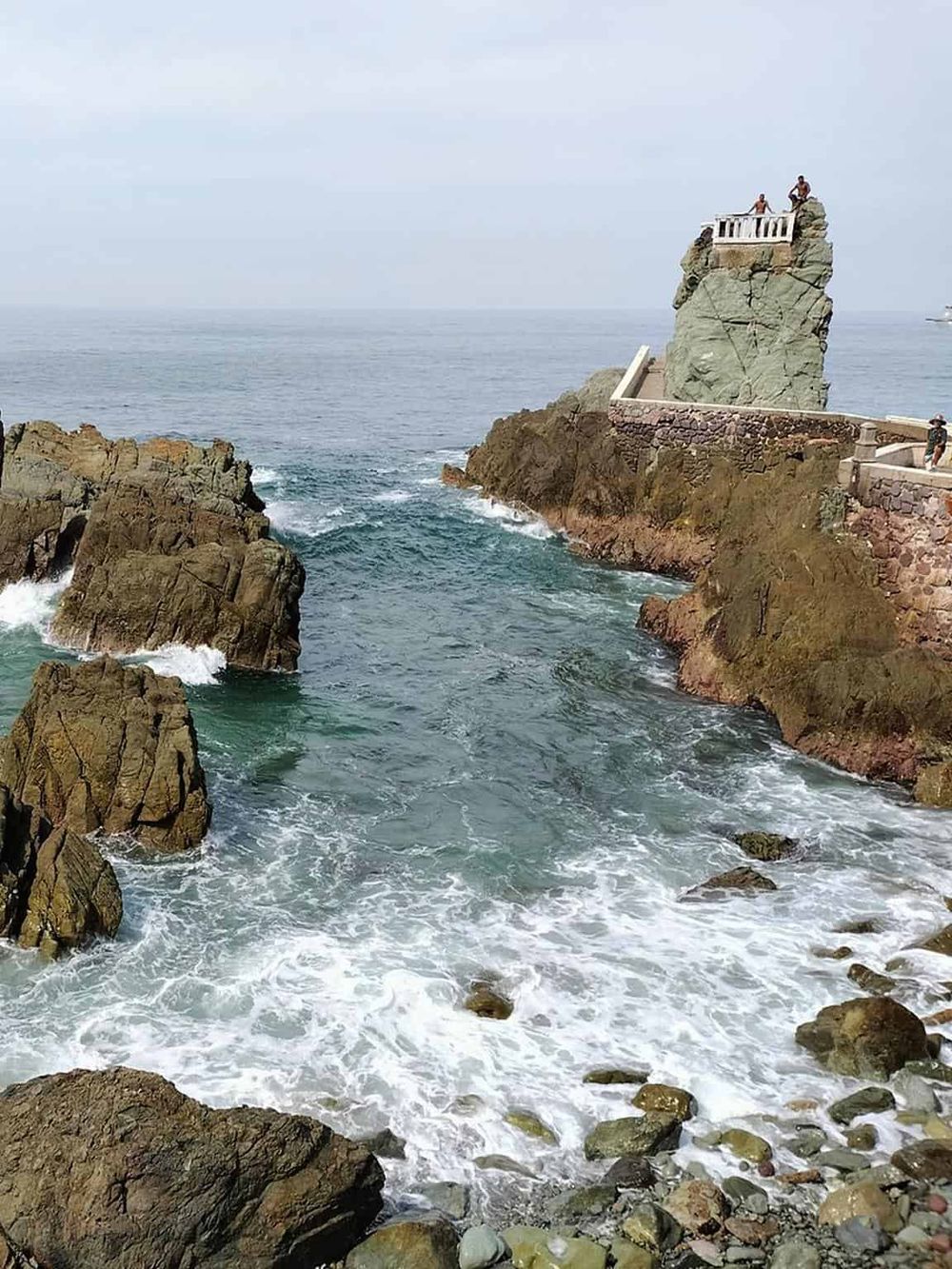 Cliffside ocean view with lighthouse and rocky shoreline, popular for sightseeing and coastal photography.