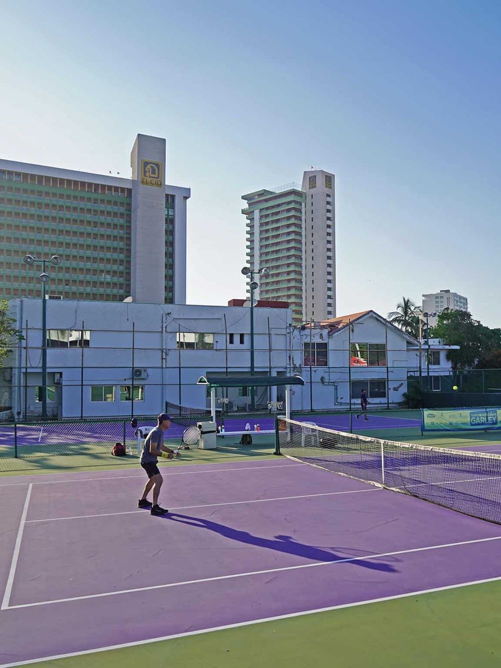 Tennis court with players, city skyscrapers in the background, Sunny day, Urban sports recreation.