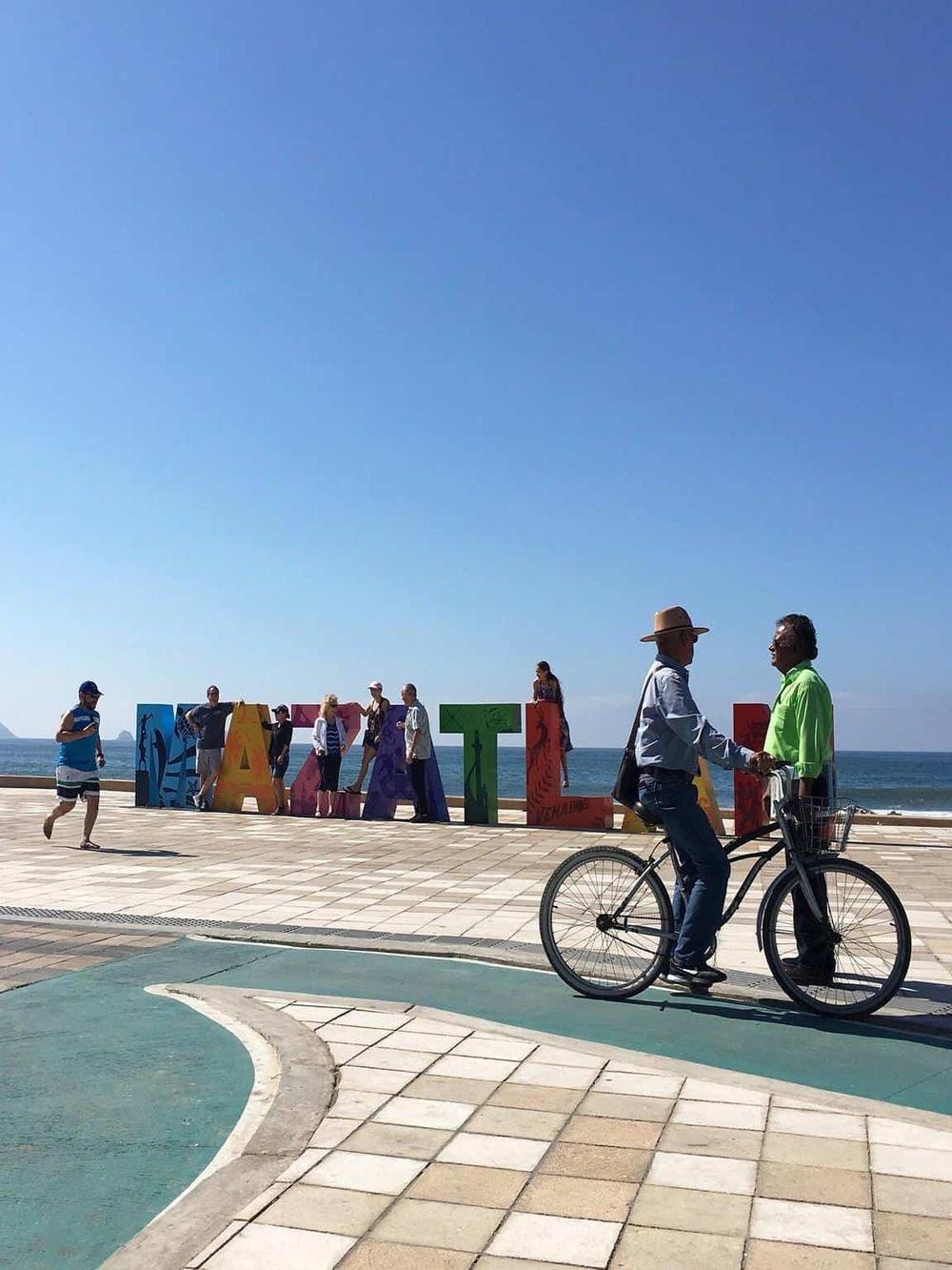 Vibrant Atlantic City beachfront with people enjoying the sunny day and iconic colorful sign.