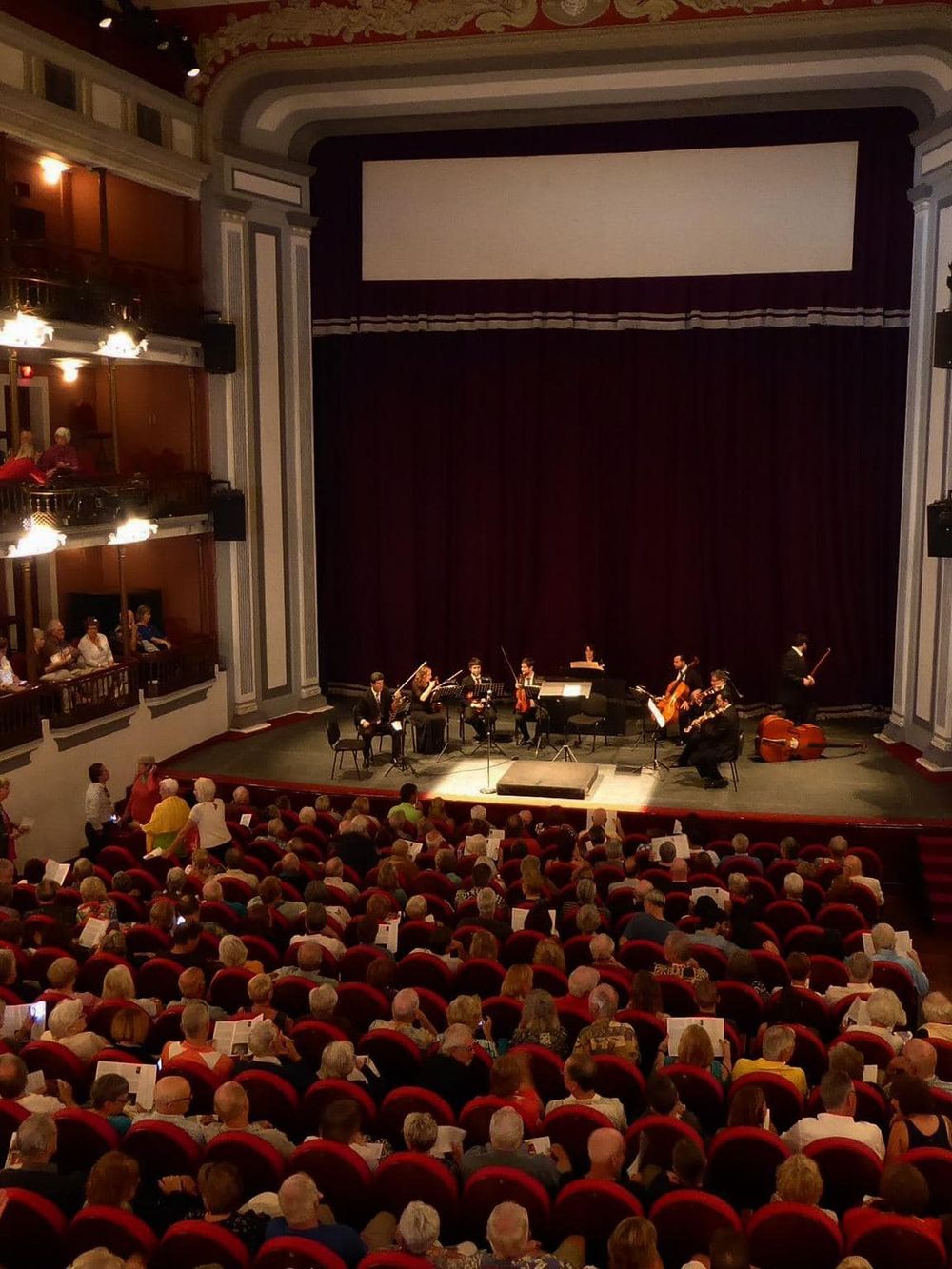 Live classical music concert at an elegant theater with audience and string quartet performance.